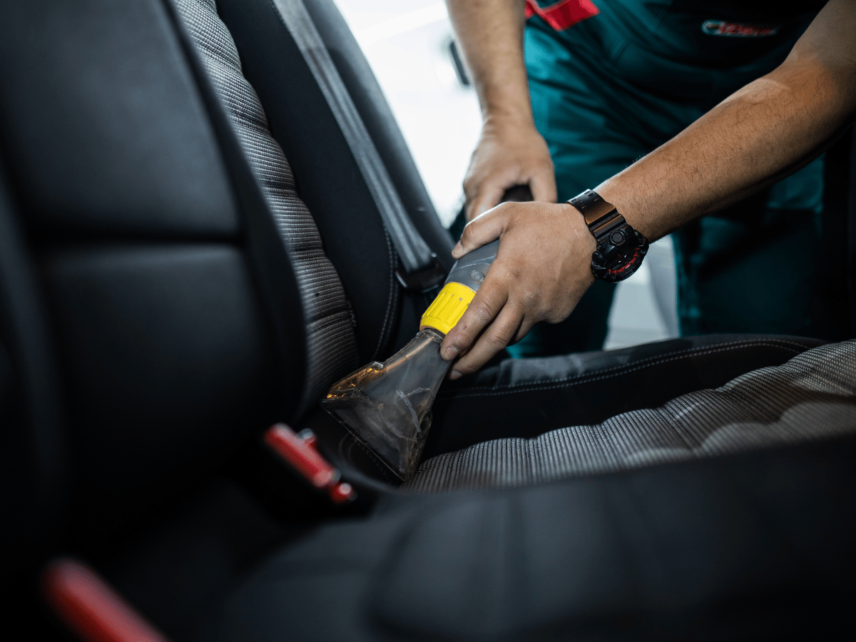 Vacuuming, wiping surfaces, and sanitising the car’s interior 